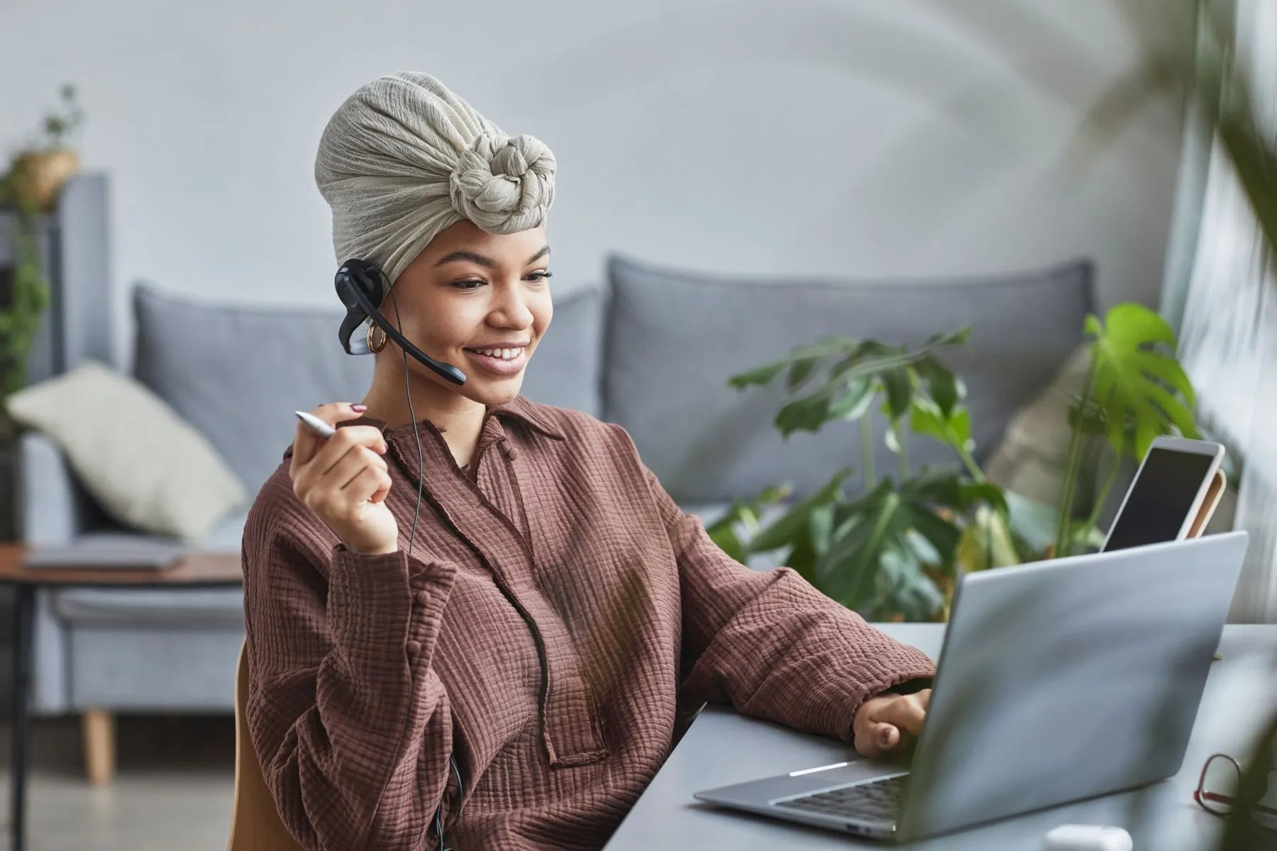 Smiling specialist with a headset working from a cozy home office